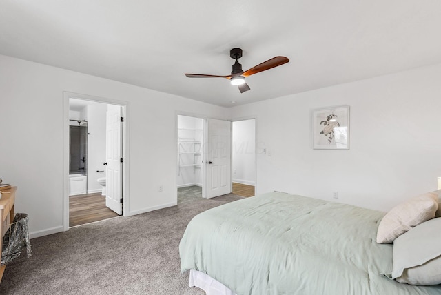 bedroom with ensuite bathroom, carpet floors, a ceiling fan, baseboards, and a spacious closet