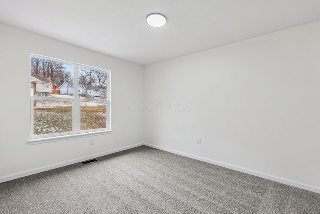 carpeted spare room featuring visible vents and baseboards