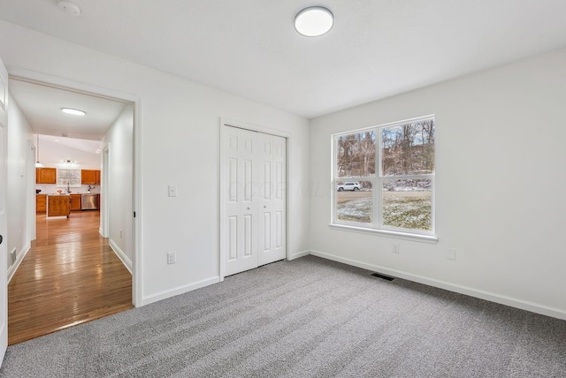 unfurnished bedroom featuring carpet, a closet, visible vents, and baseboards