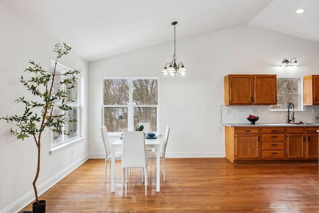 unfurnished dining area with light wood-type flooring, a wealth of natural light, vaulted ceiling, and a sink