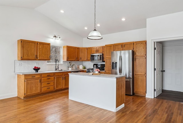 kitchen with stainless steel appliances, brown cabinets, light countertops, and a sink