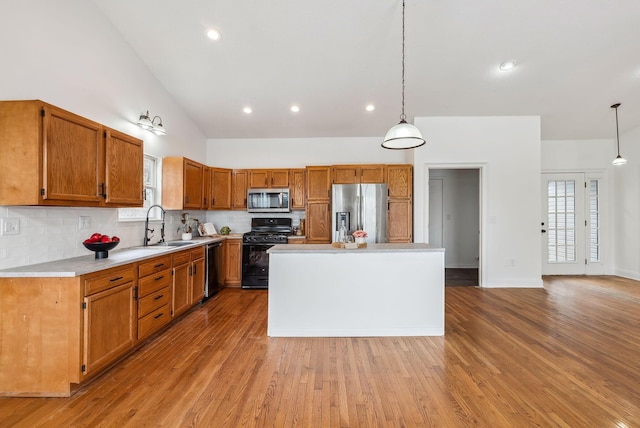 kitchen featuring appliances with stainless steel finishes, a sink, light countertops, light wood-type flooring, and backsplash