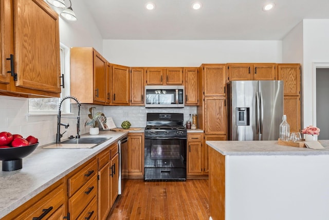 kitchen featuring appliances with stainless steel finishes, brown cabinetry, a sink, and light countertops