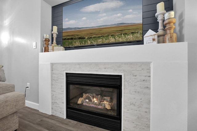 interior details featuring a glass covered fireplace, baseboards, and wood finished floors