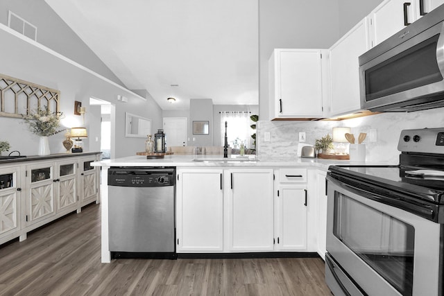 kitchen with stainless steel appliances, visible vents, white cabinets, a sink, and a peninsula