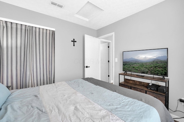 bedroom with attic access, visible vents, and a textured ceiling