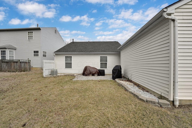 rear view of property with a lawn, fence, and central air condition unit