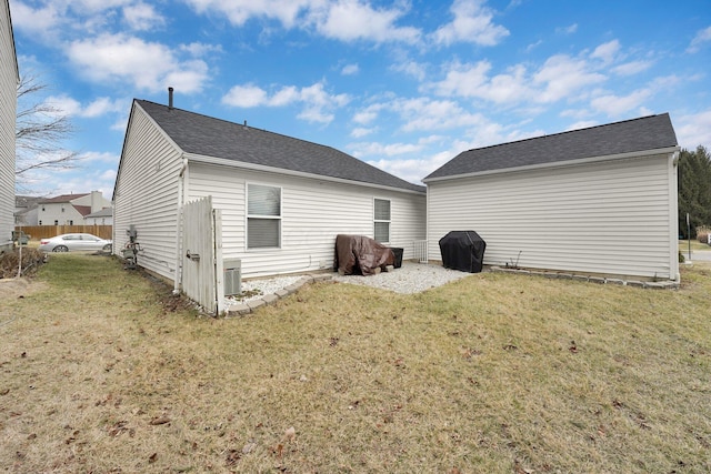 rear view of property with cooling unit and a yard