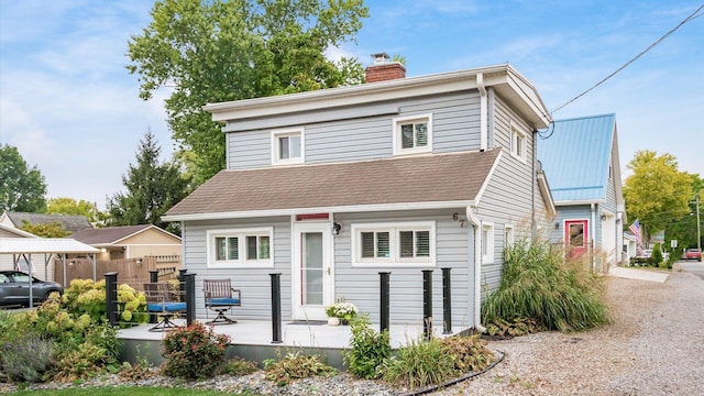 view of front of house featuring a chimney and fence