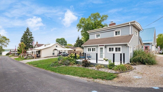 view of front facade with a residential view, a chimney, and a front lawn