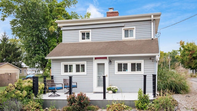 rear view of property with roof with shingles and a chimney