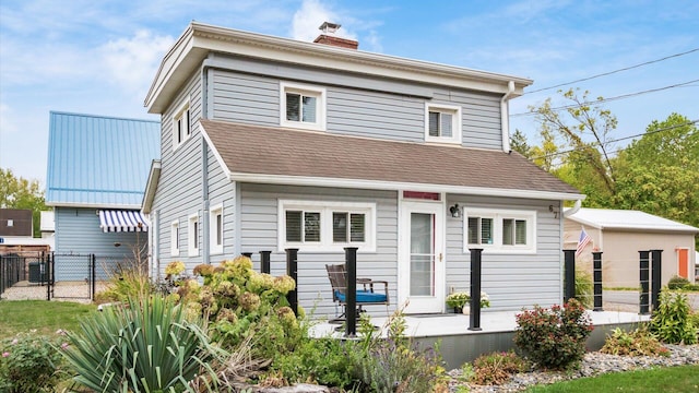 exterior space with a gate, a shingled roof, a chimney, and fence