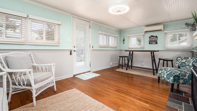 foyer featuring an AC wall unit, ornamental molding, wainscoting, and wood finished floors