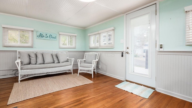 interior space with ornamental molding, a wainscoted wall, and wood finished floors