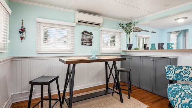 interior space with a wainscoted wall, a wall mounted AC, wood finished floors, and crown molding