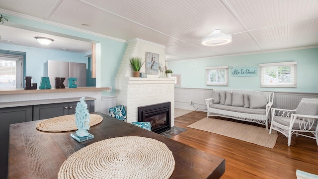 interior space featuring crown molding, a wainscoted wall, a fireplace, and wood finished floors