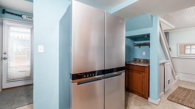 kitchen with a wainscoted wall, open shelves, light tile patterned flooring, and brown cabinets