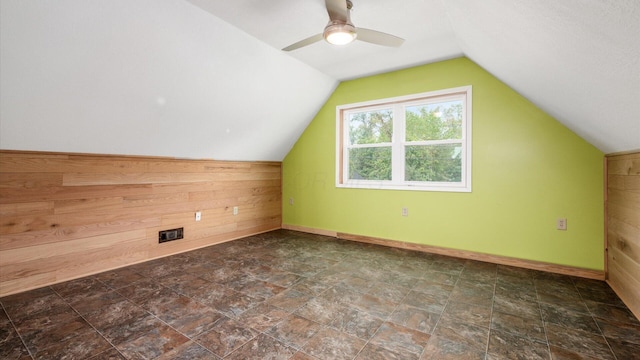 additional living space featuring ceiling fan, wooden walls, baseboards, and vaulted ceiling