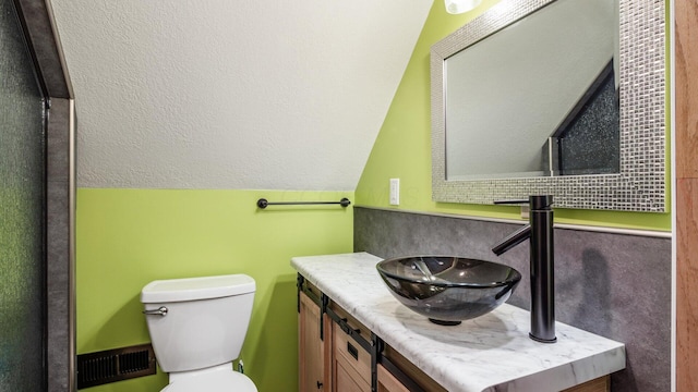 bathroom with visible vents, vaulted ceiling, vanity, and toilet