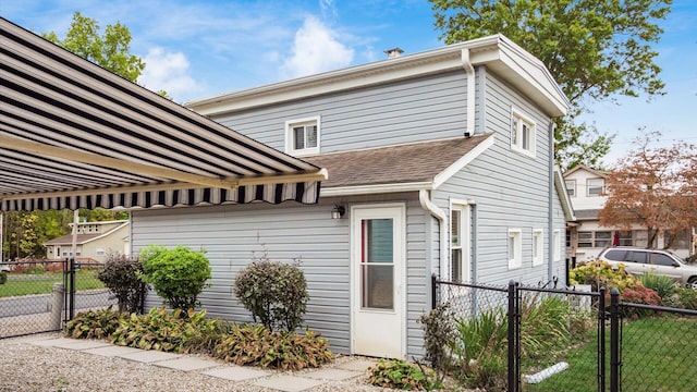 exterior space featuring a shingled roof, a gate, and fence