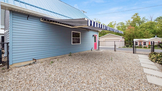 view of home's exterior with a gate, a standing seam roof, metal roof, fence, and an outdoor structure