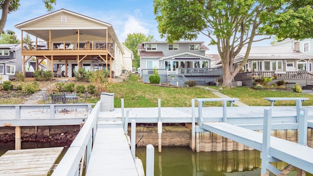 view of dock with stairs, a lawn, and a deck with water view