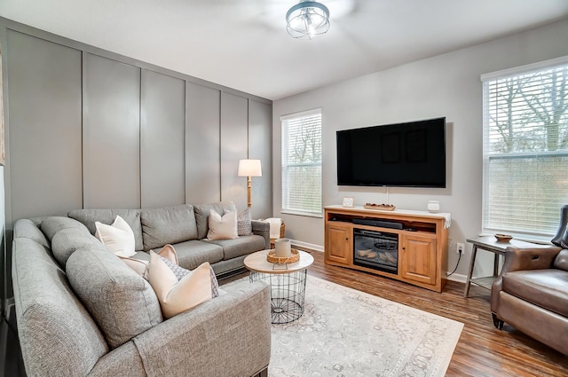 living room featuring light wood finished floors, plenty of natural light, and a decorative wall