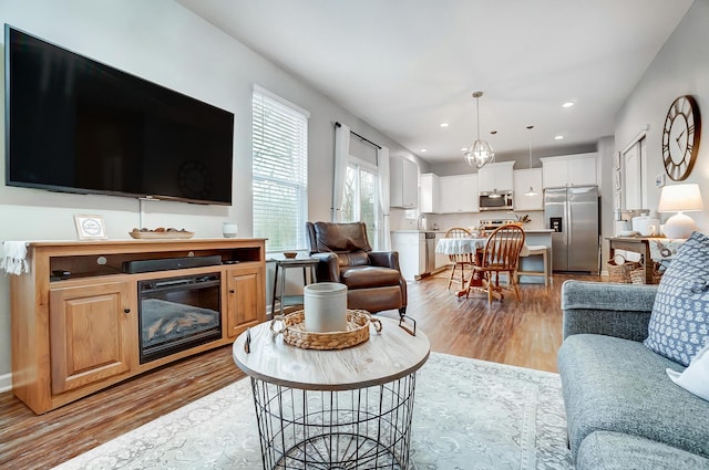 living room featuring light wood-type flooring, recessed lighting, and a glass covered fireplace