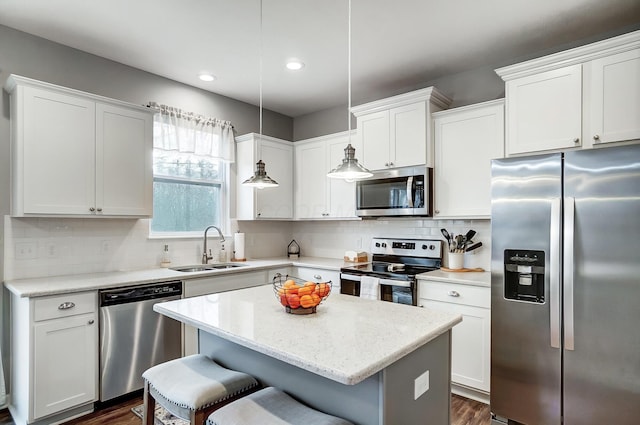 kitchen featuring a center island, stainless steel appliances, decorative backsplash, a sink, and a kitchen bar