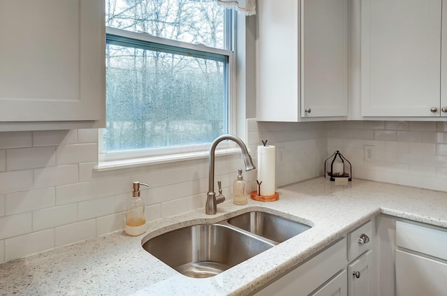 kitchen featuring decorative backsplash, a sink, a wealth of natural light, and white cabinetry