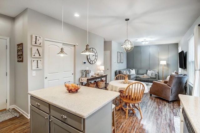 kitchen featuring a center island, dark wood finished floors, hanging light fixtures, gray cabinetry, and open floor plan