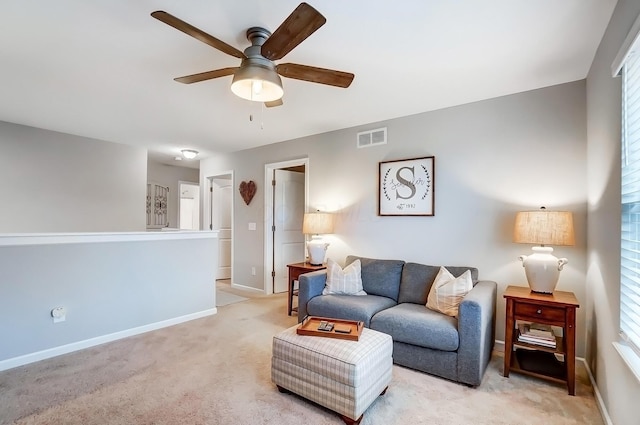 living area featuring a ceiling fan, visible vents, light carpet, and baseboards