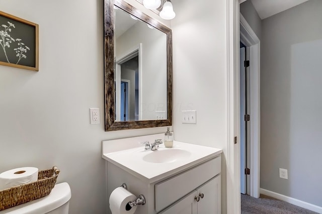 bathroom featuring toilet, baseboards, and vanity