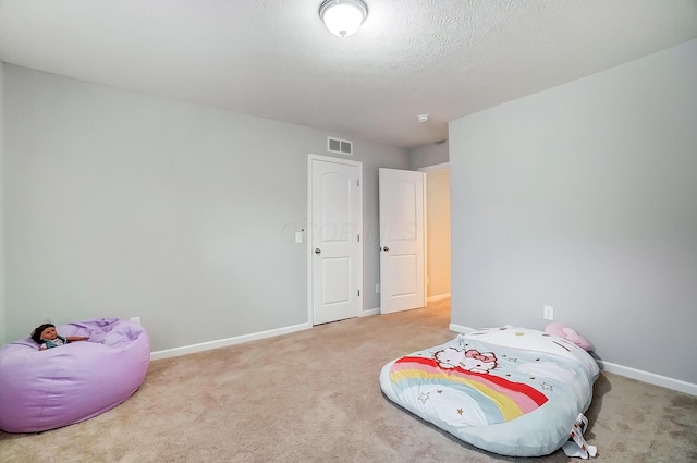 bedroom with carpet, visible vents, a textured ceiling, and baseboards