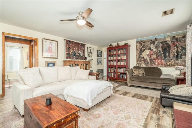 living room featuring visible vents, ceiling fan, and wood finished floors