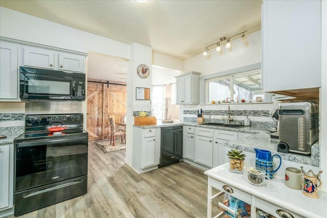 kitchen with decorative backsplash, light wood-style flooring, black appliances, and a sink