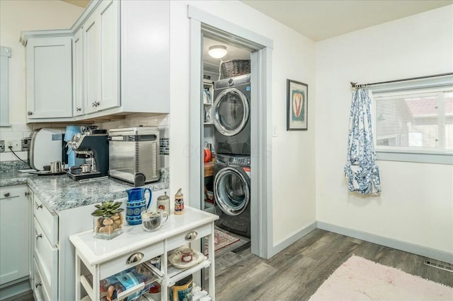 laundry room with visible vents, baseboards, laundry area, wood finished floors, and stacked washer / drying machine