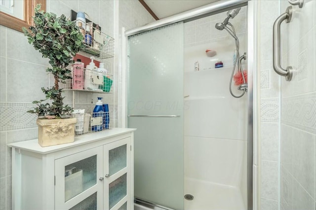 bathroom with tile walls and a stall shower