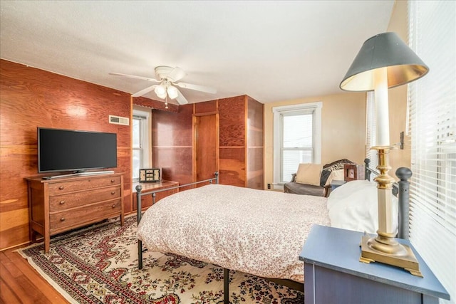 bedroom featuring ceiling fan, visible vents, and wood finished floors