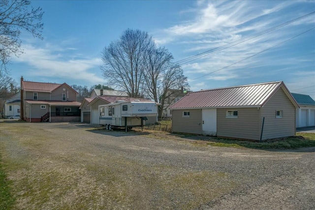 view of front facade with metal roof, an outbuilding, a garage, and a standing seam roof