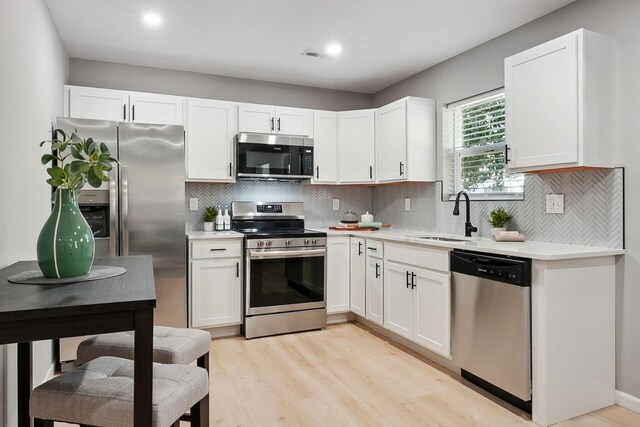 kitchen featuring light countertops, appliances with stainless steel finishes, a sink, and white cabinets