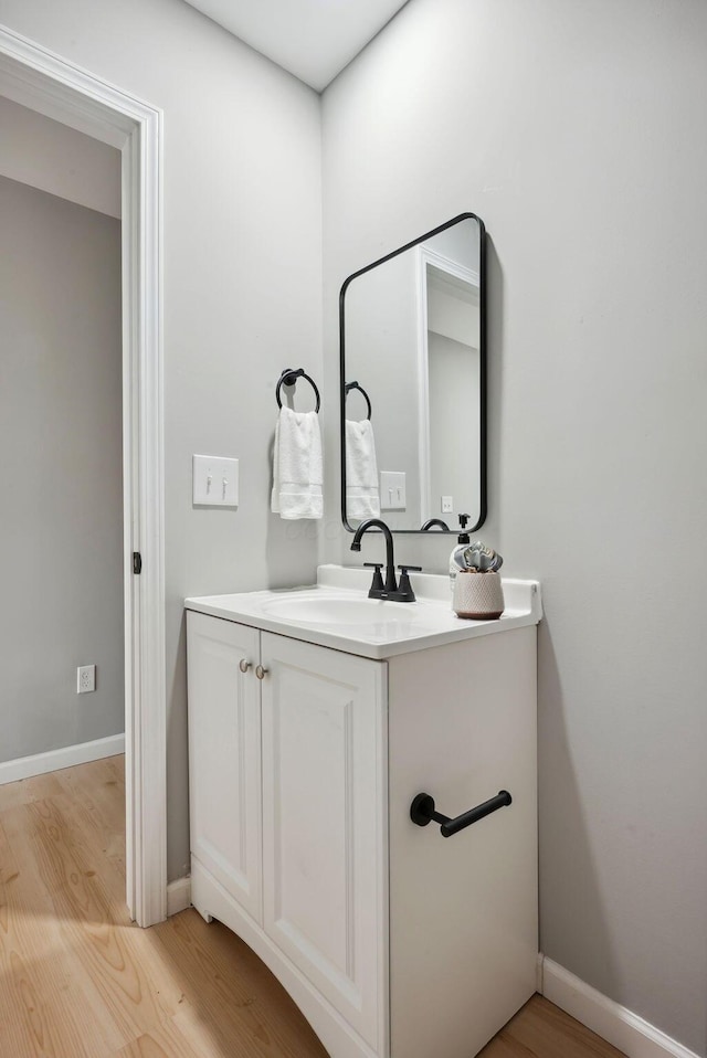 bathroom with wood finished floors, vanity, and baseboards