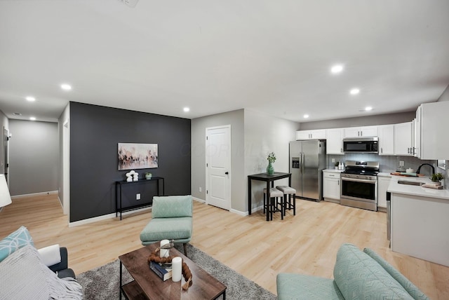 living room featuring baseboards, light wood-type flooring, and recessed lighting