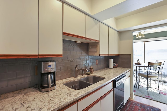 kitchen featuring dishwashing machine, a ceiling fan, a sink, decorative backsplash, and cream cabinetry