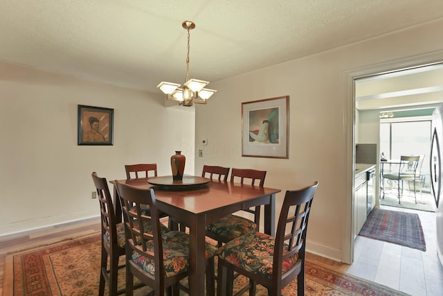 dining area with baseboards, a textured ceiling, and light wood finished floors