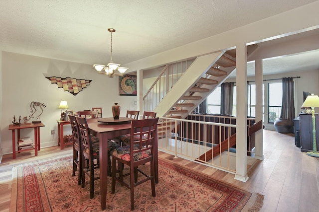 dining space with stairway, baseboards, light wood-style floors, a textured ceiling, and a chandelier