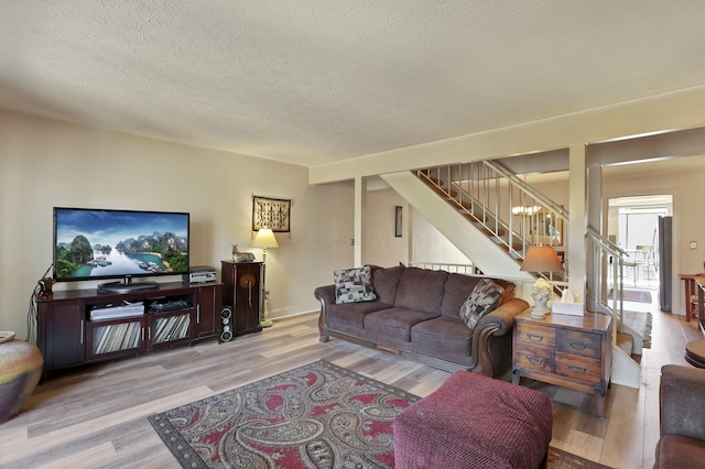 living area featuring stairway, plenty of natural light, a textured ceiling, and wood finished floors