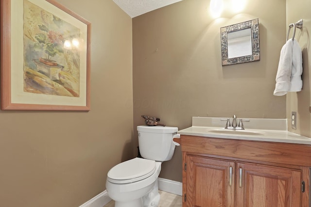 half bath featuring baseboards, toilet, and vanity