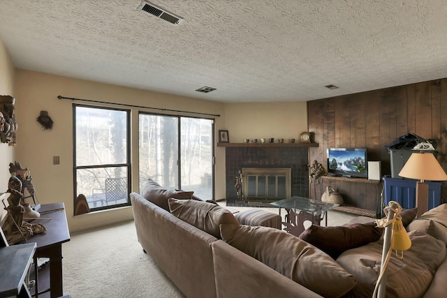 living area featuring visible vents, light carpet, a textured ceiling, and a brick fireplace