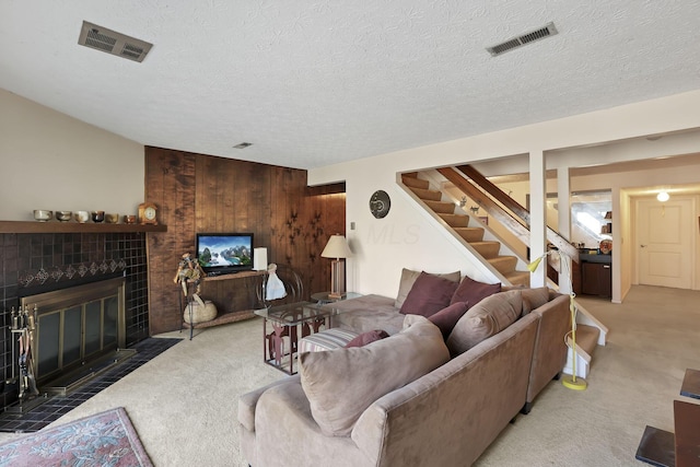 living area with visible vents, a fireplace, stairs, and carpet